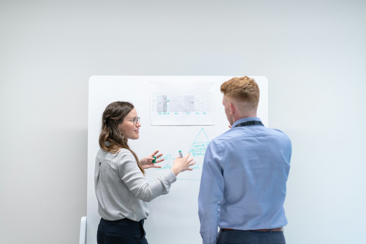 Deux personnes qui travaillent ensemble devant un tableau blanc